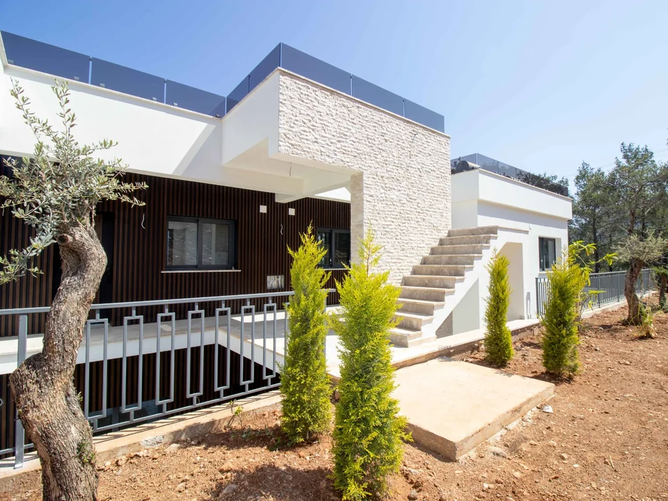 The stone and timber exterior of Nova’s Esentepe showhouses, with an outdoor staircase and olive trees