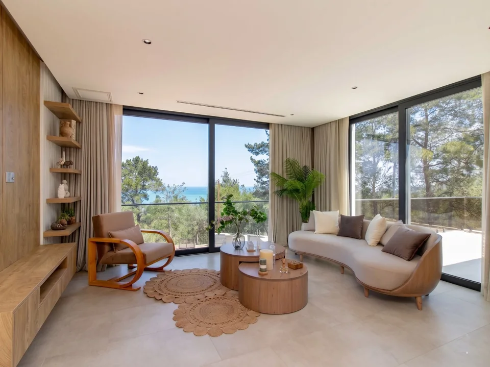 An Esentepe showhouse living room with a curved cream sofa, full-height curtains and a sea view